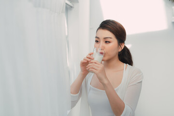 Young woman drinking milk after wake up in the morning