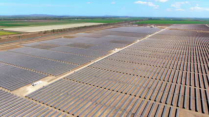 drone aerial view of vast solar energy farm with agriculture fields in countryside background. - 452169496