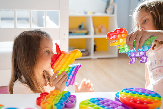 Little girls,kids,sisters play with colorful pop it children room,bedroom.Funny trendy silicone antistress colorful sensory push toy popit.Flapping fidget.Rainbow color.Cure of autism.Stress reliever