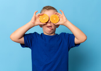 Cute little boy with citrus fruit on blue background