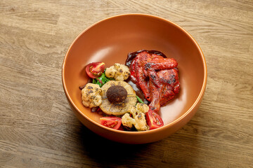 Fried chicken in Indian spices, with pineapple, broccoli and cherry tomatoes in a plate on a wooden background