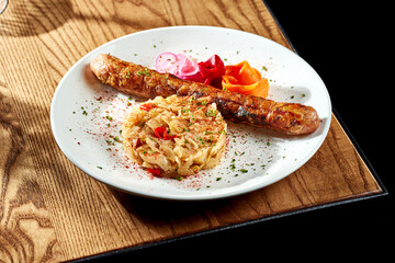 Grilled sausages with sauerkraut in a white plate on a wooden table. Currywurst