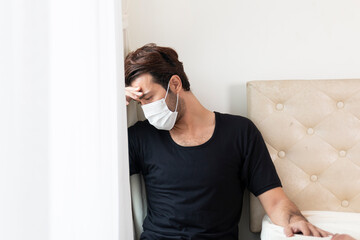 Unhappy depressed caucasian male in bed room during quarantine. Male suffering from depression and anxiety feeling overwhelmed and helpless during coronavirus (Covid-19) outbreak. Sad male at home.