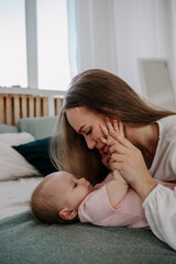 mom is lying on the bed with her baby daughter and hugs