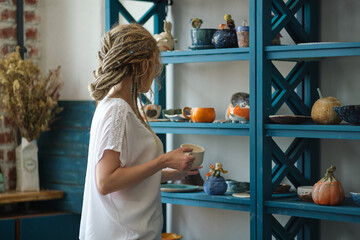 hostess of the ceramic workshop lays out her ceramic dishes on the shelves. feng shui concept....