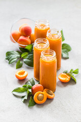 Apricot smoothies in tall glass bottles on a light gray background