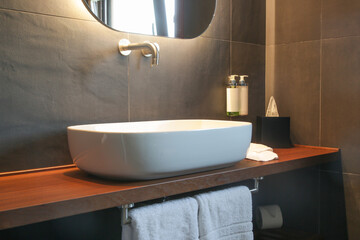 Modern simple bathroom with white bathroom sink standing on wooden shelf and backlit mirror