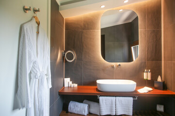Modern simple bathroom with white bathroom sink standing on wooden shelf and backlit mirror