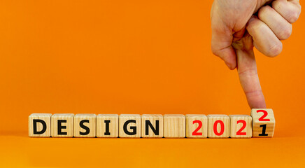 Planning 2022 design new year symbol. Businessman turns wooden cubes and changes words 'design 2021' to 'design 2022'. Beautiful orange background, copy space. Business, 2022 design new year concept.