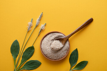Psyllium, isfagula plant product is the husk of plantain seeds in a plate on a yellow background. Useful dietary supplement, superfood. Top view, horizontal orientation, without people, copy space.  © Юлия Падина