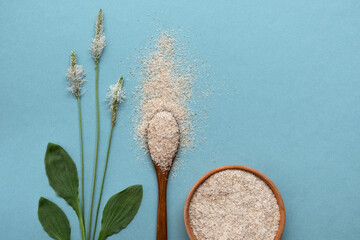 Psyllium plant product is the husk of plantain seeds in a plate and a wooden spoon on a blue background. Is a useful dietary supplement, a superfood. Top view, horizontal orientation, copy space. © Юлия Падина