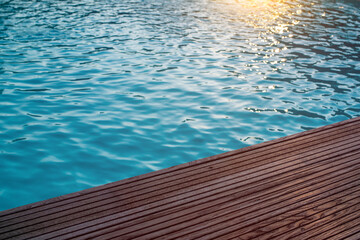 Hintergrund Poolwasser im Sonnenuntergang mit Holzdielen als Beckenrand