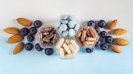 Various capsules with dietary supplements or vitamines and fresh blueberry and nuts