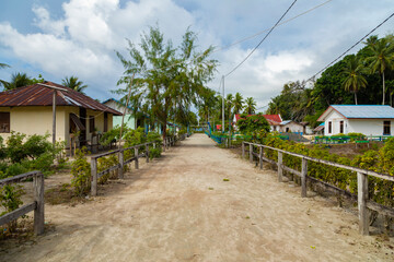 Fototapeta na wymiar One of the streets in the small town of Friwin, surrounded by humble little houses and tropical green plants, Raja Ampat, West Papua, Indonesia