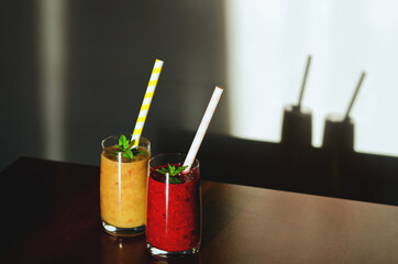 Top view of two different fresh healthy smoothies in a glasses made of peach, banana and berries with mint. Creative concept of healthy detox drink, diet or vegetarian food concept. Copy space.