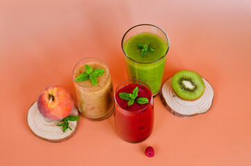 Top view of three different fresh delicious smoothies in a glasses made of peach, banana and berries with mint. Creative concept of healthy detox drink, diet or vegetarian food concept. Copy space.