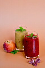 Top view of two different fresh healthy smoothies in a glasses made of peach, banana and berries with mint. Creative concept of healthy detox drink, diet or vegetarian food concept. Copy space.