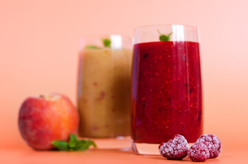 Top view of two different fresh healthy smoothies in a glasses made of peach, banana and berries with mint. Creative concept of healthy detox drink, diet or vegetarian food concept. Copy space.
