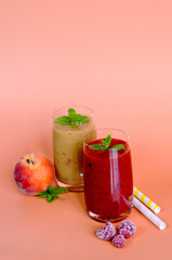 Top view of two different fresh healthy smoothies in a glasses made of peach, banana and berries with mint. Creative concept of healthy detox drink, diet or vegetarian food concept. Copy space.