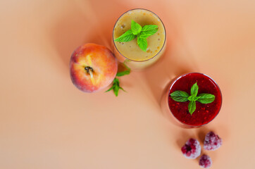 Top view of two different fresh healthy smoothies in a glasses made of peach, banana and berries with mint. Creative concept of healthy detox drink, diet or vegetarian food concept. Copy space.
