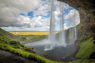 Seljalandsfoss waterfall, Southern Iceland. Long exposure, sunny summer day with white puffy clouds