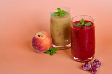 Top view of two different fresh healthy smoothies in a glasses made of peach, banana and berries with mint. Creative concept of healthy detox drink, diet or vegetarian food concept. Copy space.