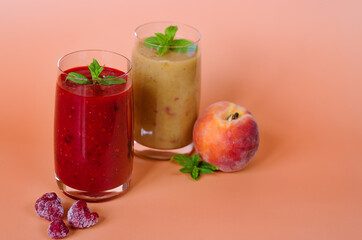 Top view of two different fresh healthy smoothies in a glasses made of peach, banana and berries with mint. Creative concept of healthy detox drink, diet or vegetarian food concept. Copy space.