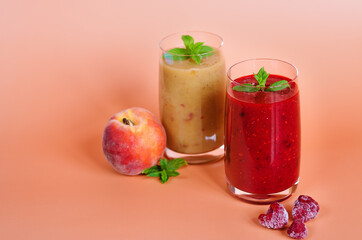 Top view of two different fresh healthy smoothies in a glasses made of peach, banana and berries with mint. Creative concept of healthy detox drink, diet or vegetarian food concept. Copy space.