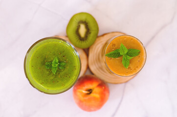 Top view of two different fresh healthy smoothies in a glasses made of peach, banana and berries with mint. Creative concept of healthy detox drink, diet or vegetarian food concept. Copy space.