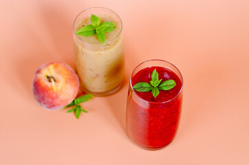 Top view of two different fresh healthy smoothies in a glasses made of peach, banana and berries with mint. Creative concept of healthy detox drink, diet or vegetarian food concept. Copy space.