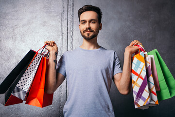 Man hold hands many bags shopper european dressed plain t-shirt carrying enjoying new clothes packs...