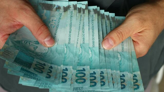 Counting Brazilian money, Lots of banknotes of one hundred reais, close up. Financial concept 