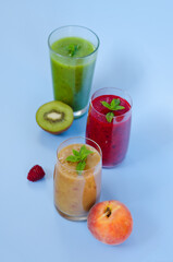 Top view of three different fresh delicious smoothies in a glasses made of peach, banana and berries with mint. Creative concept of healthy detox drink, diet or vegetarian food concept. Copy space.