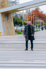 Handsome young man walking down the street. Confident businessman walking outdoor during the autumn. Stock photo