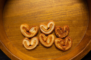 top view of many delicious freshly baked puff pastry ears on a wood colored board
