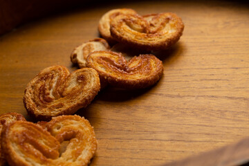 close up of many delicious freshly baked puff pastry ears on a wood colored board