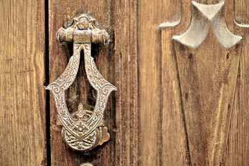 Ornate metal door knocker, old wooden door, text space to the right.
