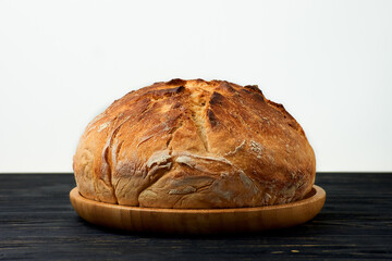 Fresh homemade wheat bread on wooden plate on black wooden table