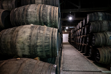 Old porto lodge with rows of oak wooden casks for slow aging of fortified ruby or tawny porto wine in Vila Nova de Gaia, Portugal