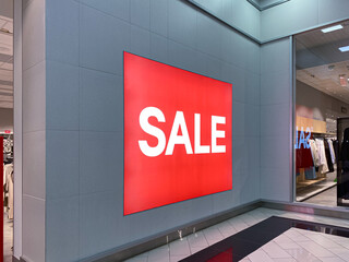 A huge red poster with the inscription - Sale. On the gray wall. There are big discounts in the store