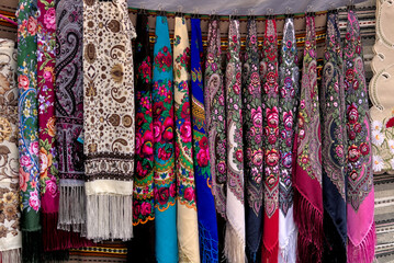 Fototapeta na wymiar A set of colorful Ukrainian headscarves hanging at a street fair. National Ukrainian clothing. An important accessory for women.