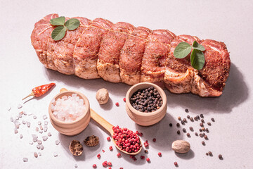 A piece of raw pork loin, marinated fresh meat tied with culinary twine with spices