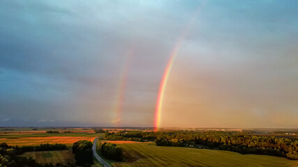 Double Rainbow Over Forest and Wheat Field. Dark Thunderstorm Clouds and Rainbow Over Rural Highway Road Landscape. Camera Moves Backward. Aerial Shot