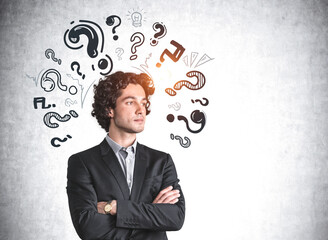 Serious businessman is standing near sketch with question marks