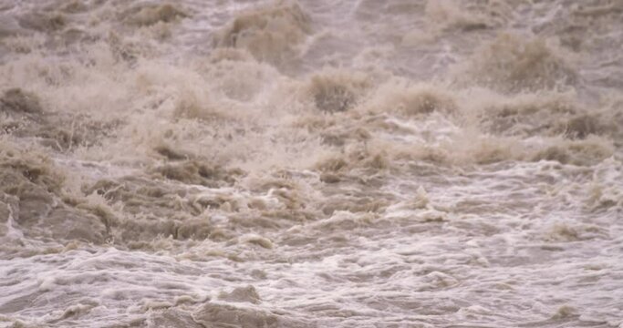 スローモーション - 大雨で堰から溢れる泥水から洪水の瓦礫へ チルトダウン