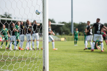 Detail of goal's post with net and football players during free kick in the background.