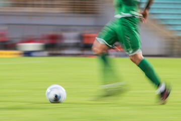 Football player runs with ball during match - blurred motion due to long exposure