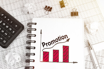 On the table is a calculator, a pen and a notebook with a graph and an inscription - Promotion