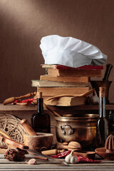 Fototapeta na wymiar Chef's hat, vintage cookbooks, and old kitchen utensils on the kitchen table.