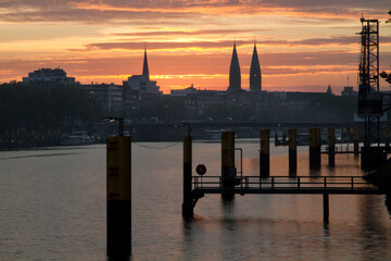 Fototapeta premium Beautiful sunrise with dramatic sky at the River Weser in Bremen, Germany with church towers at the city scape